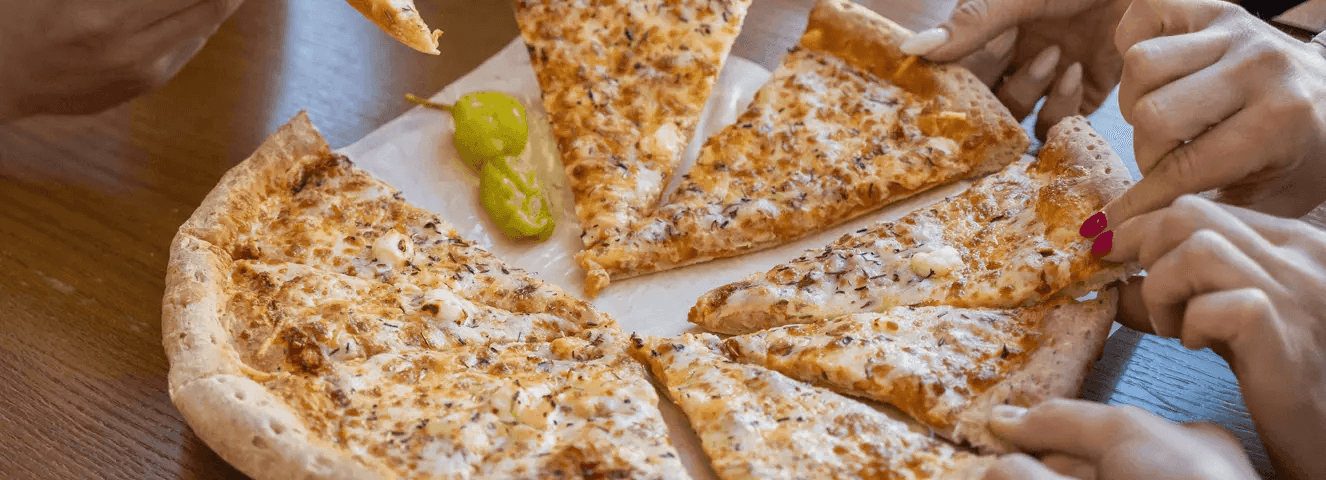 manos de gente agarrando porciones de pizza